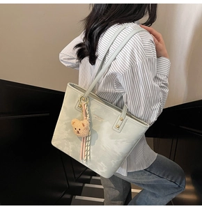 Pale green marble pattern tote bag with teddy bear charm shown on model's shoulder