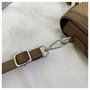 Detailed macro view of dark brown leather handbag strap with silver metal buckle and clasp