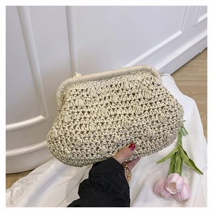 Detail of hand-woven cream clutch bag texture and gold chain strap for beach vacations