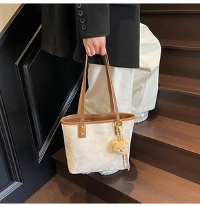 Detail of a marble pattern tote bag with brown leather trim and cute bear charm