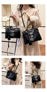 Detail view of black leather tote bag with silver metal twist lock and hanging tag