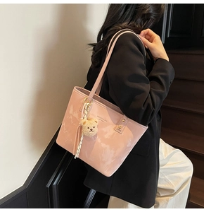 Detail of pink marble pattern tote bag featuring a cute teddy bear charm on model's shoulder