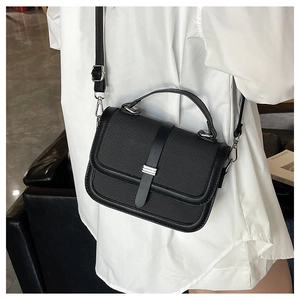 Detail of black woven texture crossbody bag with silver hardware on a lifestyle model