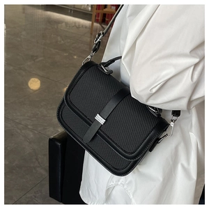 Detail showing woven texture on a black crossbody bag with silver metal hardware