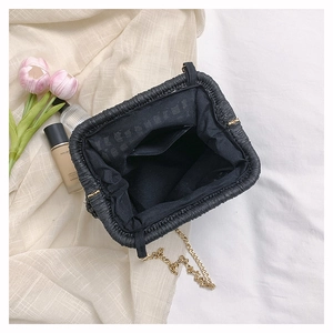 Top view of black woven straw handbag showing fabric lining and golden chain strap