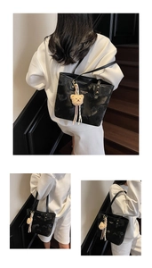 Detail of black tote bag with white lettering, gold rivets, and a plush bear charm accessory