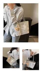 Detail of silver metallic tote bag with marble texture and bear charm accessory