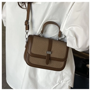 Side view of a brown woven flap crossbody bag with adjustable strap on a female model