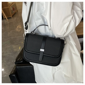 Detail of black quilted leather crossbody bag with silver buckle and adjustable strap