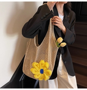 Detail of beige hollow woven tote bag with yellow knit sunflower held by a model