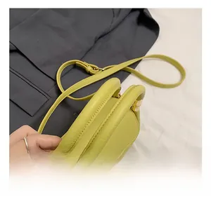 Detail of light green litchi texture leather bag with white lace trim and gold hardware