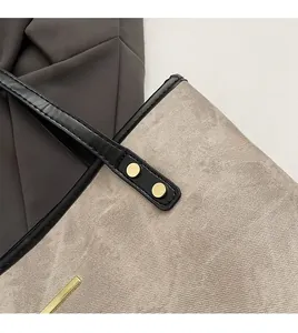 Detail of beige twill fabric tote with black leather strap and gold metal rivets