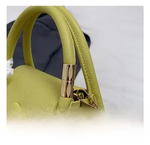 Close-up of golden metal hooks and lychee leather texture on a green handbag
