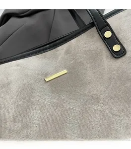 Detail of gray textured fabric tote with gold hardware and black leather straps