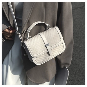 Detailed texture of cream crossbody bag paired with a gray suit for a minimalist look