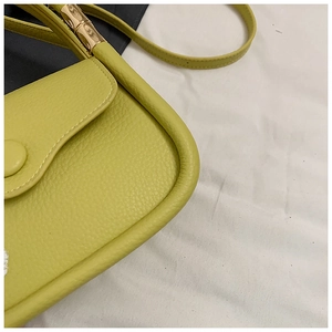 Detail of light green litchi texture leather bag with golden bamboo metal hardware