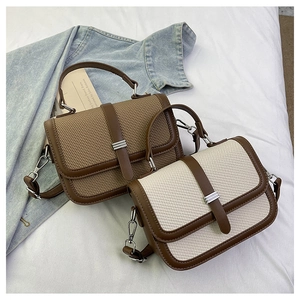 Close-up of retro fabric flap bag with brown leather trim and silver metal buckle