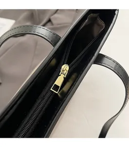Detail view of smooth golden zipper and premium black synthetic leather on a tote bag