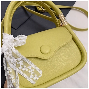Close-up of lime green litchi grain leather tote bag with lace bow and bamboo handle