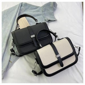 Detail view of woven leather texture and silver buckle on two-tone crossbody bags