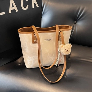 Minimalist marble pattern tote bag with leather straps and bear charm on a sofa
