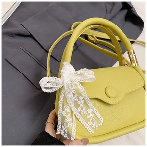 Detail of lychee textured leather mini tote bag with a white lace bow on the handle