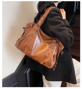 Detail of vintage brown PU leather tote bag with metallic studs and soft pleated texture