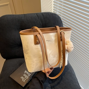 Large beige tote bag with marble pattern and brown leather straps on a sofa