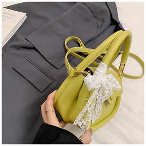Detailed shot of yellow faux leather crossbody bag featuring a lace bow and gold hardware