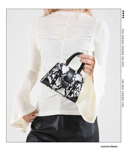 Detail view of mini snake print handbag with black leather trim and gold metal rivets