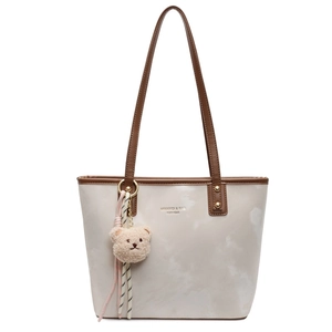 Stylish marbled beige tote bag with brown leather handles and a plush bear charm