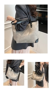 Detail of grey textured canvas tote bag with black leather reinforcement and long straps
