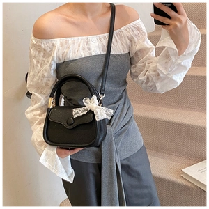 Detail showing classic black lychee leather bag texture and white lace bow charm