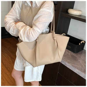 Detail of large beige tote bag with litchi texture and unique knot handle decoration