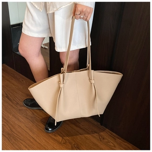 Detail of beige wing tote bag with knot strap and textured faux leather for daily use