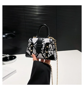 Detail of snake skin pattern mini handbag with gold rivets and metallic chain strap