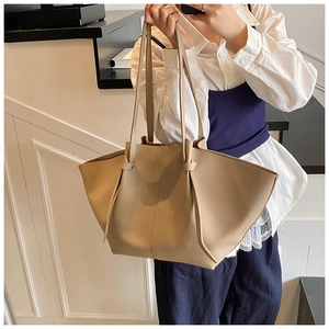 Detail view of the beige pebbled leather texture and side tie accents on the tote bag
