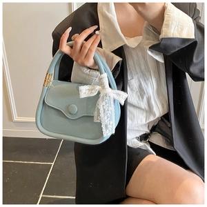 Detail of light blue leather tote bag with white lace bow and golden hardware
