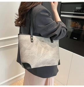 Detail of large tie-dye tote bag with black leather straps and distressed grey texture