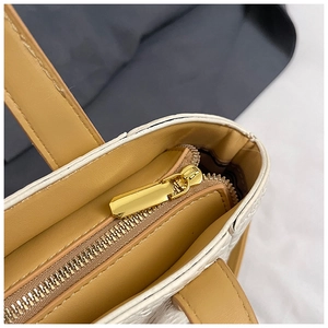 Détail de la fermeture éclair en métal doré et du cuir texturé blanc de ce sac à main