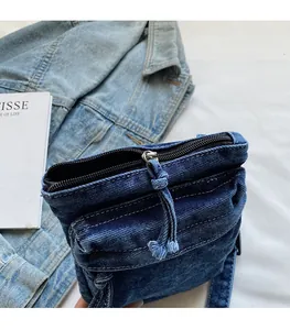 Dettaglio della cerniera nera su borsa a tracolla in denim blu scuro con cuciture a contrasto