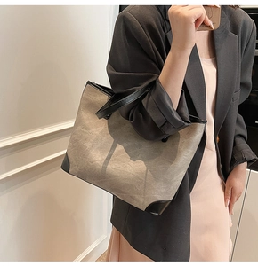 Detail view of khaki canvas tote bag with black leather trim and reinforced base