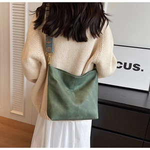 Detail of dark green tote bag featuring an embroidered colorful wide shoulder strap