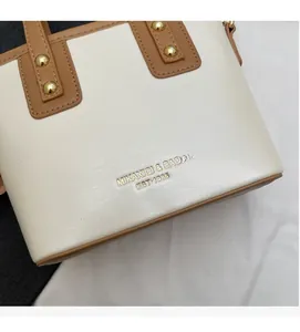 Detailed macro view of the cream and brown faux leather bucket bag with gold stud accents