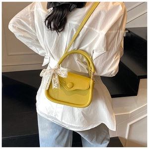 Detail of yellow leather mini square bag with elegant white lace bow on the side