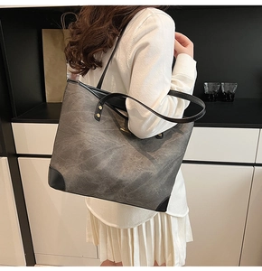 Detail of grey shoulder tote bag with cloud texture, black corner patches and rivets