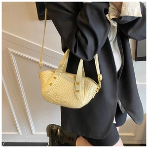 Détail d'un sac à main beige à texture tissée avec rivets dorés et bandoulière réglable