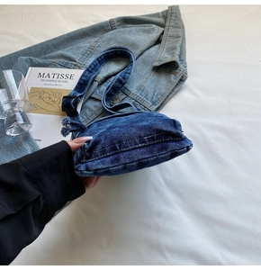 Dettaglio borsa a tracolla in denim blu con tracolla regolabile e bordi con frange