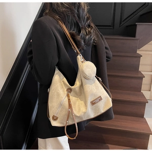 Detail of beige canvas Hobo bag with brown leather trim and round coin purse charm