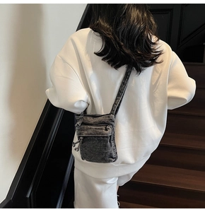Dettaglio della borsa a tracolla in denim grigio con tasche funzionali e nodi a coulisse